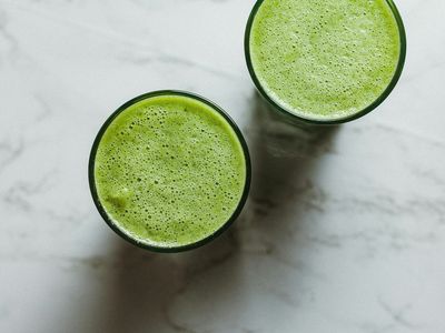 Dos vasos de batido verde vistos desde arriba sobre una mesa de mármol