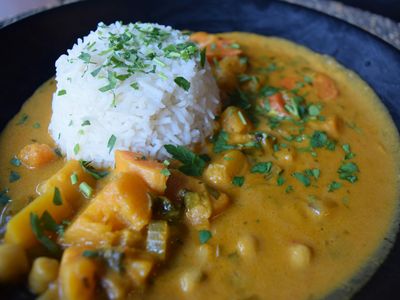 Plato de curry de garbanzos con verduras y arroz, con hierbas picadas