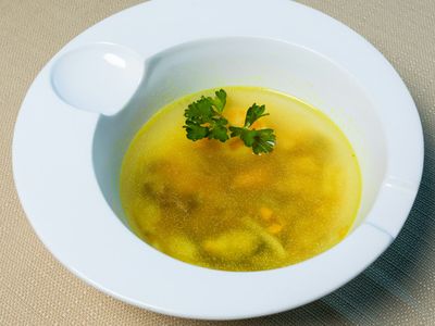 Plato hondo de caldo claro con perejil fresco