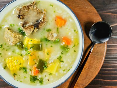 Plato de caldo con pollo, choclo, zanahoria, pimiento y arroz