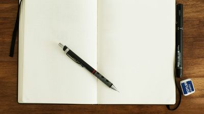 Cuaderno abierto en blanco con un lápiz sobre una mesa de madera, como se practican los códigos de Grabovoi