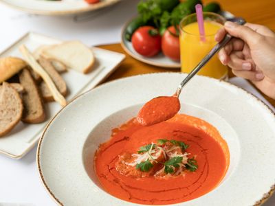 Plato de gazpacho rojo de tomate con pan y tomates frescos al lado