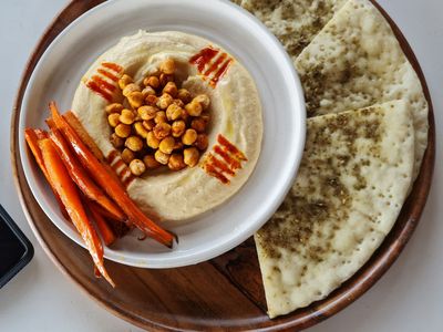 Plato de humus con garbanzos tostados, bastones de zanahoria y pan plano