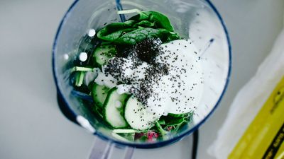 Licuadora con espinaca, pepino, yogur y semillas para un jugo verde, como los que se venden como jugos detox