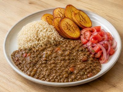 Plato de menestra de lenteja con arroz integral, maduro asado y ensalada de tomate