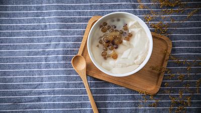 Tazón de yogur natural con cuchara de madera, un alimento fermentado para la microbiota intestinal