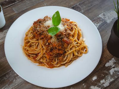 Plato de pasta con salsa boloñesa de carne y tomate, queso rallado y albahaca