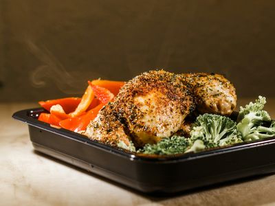 Pollo al horno con especias junto a pimiento rojo y brócoli en una bandeja