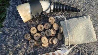 Runas talladas en discos de madera junto a una bolsa de tela, para conocer el significado de las runas