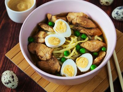 Tazón de sopa con pollo, fideos, arvejas y huevos duros en mitades