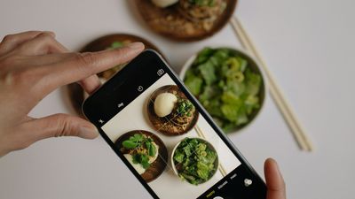 Manos tomando con el celular una foto a platos de comida saludable, como en las tendencias de salud virales