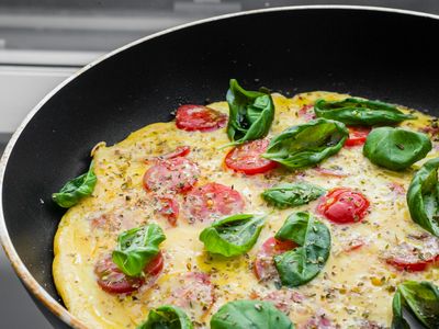 Tortilla de huevo en sartén con espinaca y tomates cherry
