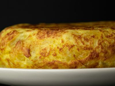 Tortilla gruesa de huevo dorada servida en un plato