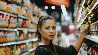 Mujer eligiendo productos en el pasillo de un supermercado, donde abundan los alimentos ultraprocesados